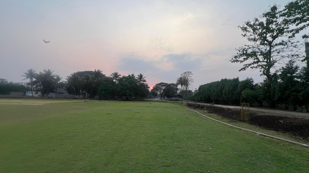 Nabhangan's wide, empty lawn at dusk, ringed by trees